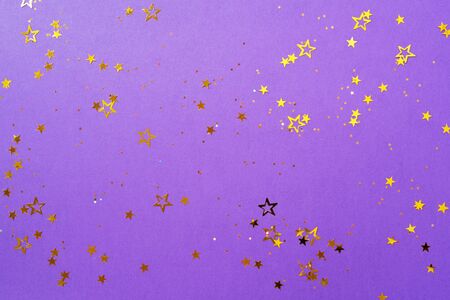 Golden star sparkles on violet background. Christmas and New year concept. Festive backdrop with copy space.の写真素材