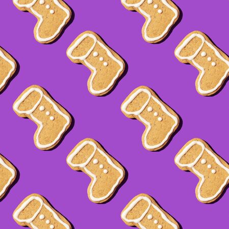 Christmas gingerbread pattern on violet background. Top view. Flat lay. Boot shapes cookies. New year and Christmas concept.の写真素材
