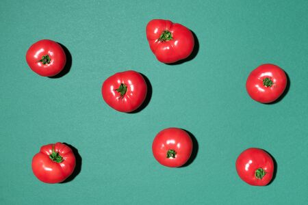 Red tomatoes pattern on green background. Flat lay, top view. Summer minimal concept. Vegan and...