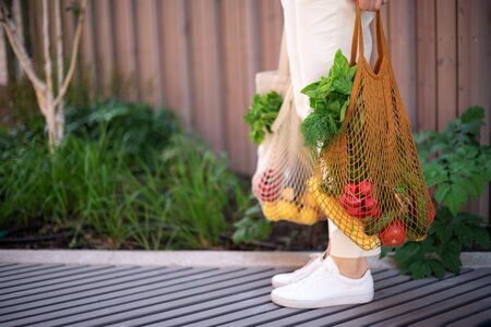 Zero waste concept with copy space. Woman holding cotton shopper and reusable mesh shopping bags with vegetables, products. Eco friendly mesh shopper. Zero waste, plastic free conceptの写真素材