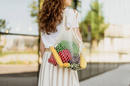 Zero waste concept with copy space. Woman holding cotton shopper and reusable mesh shopping bags with vegetables, products. Eco friendly mesh shopper. Zero waste, plastic free conceptの写真素材