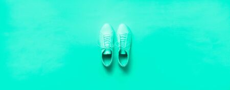 Stylish white sneakers and rope on mint color background with copy space. Top view. Minimal flat lay. Summer shoes collection. Biscay Green color of the year 2020の写真素材