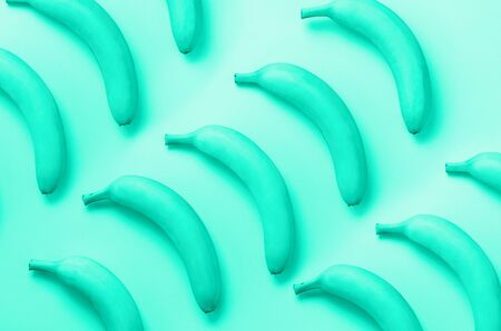 Colorful fruit pattern. Bananas over mint color background. Top view. Trendy green and turquoise...