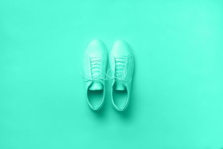 Stylish white sneakers and rope on mint color background with copy space. Top view. Minimal flat lay. Summer shoes collection. Biscay Green color of the year 2020の写真素材