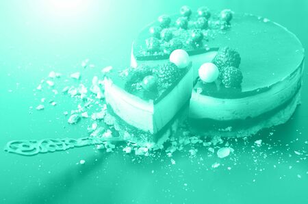 Delicious raspberry cake with fresh strawberries, raspberries, blueberry, currants and pistachios on mint color background. Trendy green and turquoise color. Copy space. Banner.の写真素材