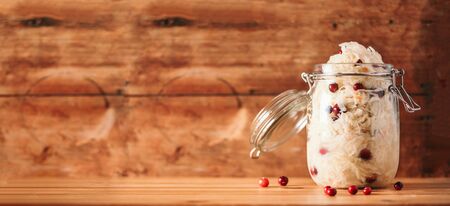 Sauerkraut in glass jar on wooden background with copy space. Fermented and marinated cabbage at home. The best natural probiotic food.の写真素材