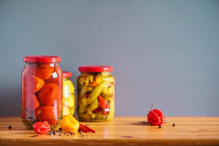 Preserved vegetables in glass jars on wooden background. Copy space. Healthy fermented food concept. Harvest concept.の写真素材