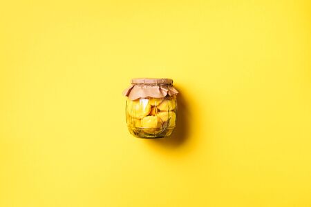 Pickled squash in glass jar over yellow background. Top view. Flat lay. Copy space. Canned and preserved vegetables.の写真素材