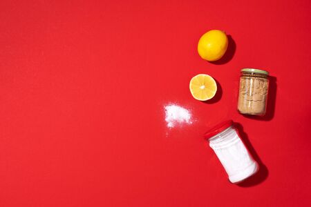 Flat lay composition with eco-friendly natural cleaners. Baking soda, salt, lemon and mustard powder on red background. Top view. Copy space. Flat lay. Homemade green cleaningの写真素材