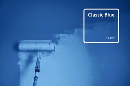 Painting wall with paint roller in monochrome color. Appartment renovation, repair, building and home concept. Trendy blue and calm color. Copy space, banner. Tools for painting wallsの写真素材