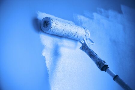 Painting wall with paint roller in monochrome color. Appartment renovation, repair, building and home concept. Trendy blue and calm color. Copy space, banner. Tools for painting wallsの写真素材
