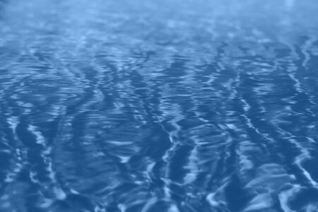 Close up abstract water texture. Swimming pool water in monochrome color background. Trendy blue and...