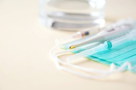 Concept of flu treatment - pills, capsules, thermometer, protective surgical mask, syringe. Copy space. Banner. Viral attack. Bunch of drugs, cold flu treatment. Coronavirus Covid-19.の写真素材