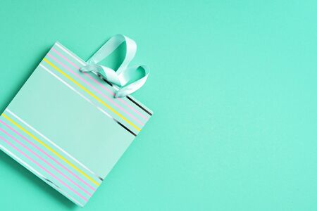 Black friday sale concept. Top view of turquoise paper shopping bag on trendy green background. Copy space. Womans day. Valentines day. Ready for birthday party.の写真素材