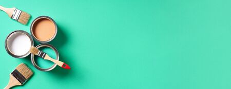 Paint brushes and open paint cans with on trendy green background. Top view, copy space. Appartment renovation, repair, building and home design concept.の写真素材