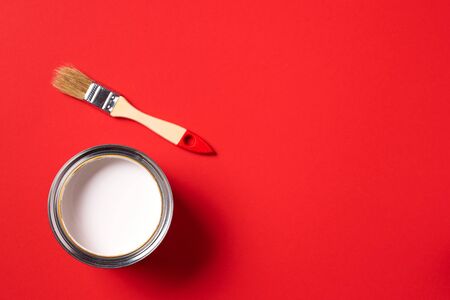 Brush and open paint can on trendy red background. Top view, copy space. Appartment renovation, repair, building and home design concept.の写真素材