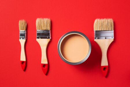 Brush and open paint can on trendy red background. Top view, copy space. Appartment renovation, repair, building and home design concept.の写真素材