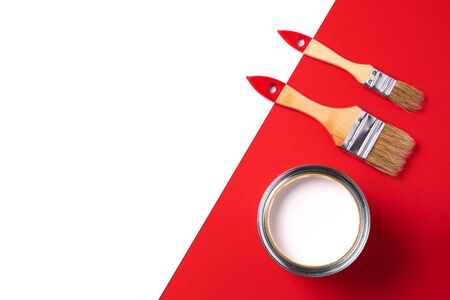 Wooden paint brushes, open paint can on trendy red and white background. Top view, copy space. Appartment renovation, repair, building and home design concept.の写真素材