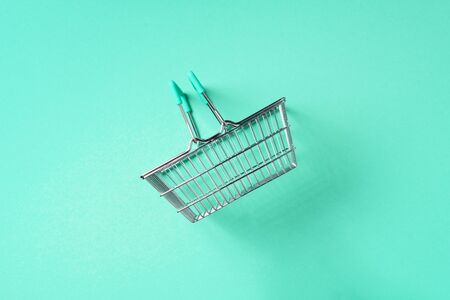 Top view of supermarket shopping basket on trendy green background. Black friday sale concept. Copy...