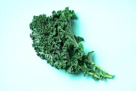 Fresh green raw kale leaves on trendy green background. Top view. Copy space. Superfood and healthy diet conceptの写真素材