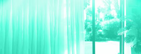 Tropical view background. Summer, travel, vacation and holiday concept in mint color. Trendy green and turquoise color. Open window, door with blurred palm garden view from hotelの写真素材