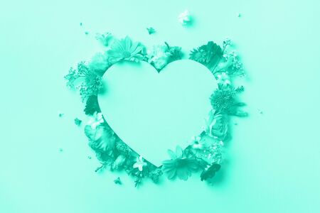 Creative layout with mint flowers, paper heart over mint color background. Top view, flat lay. Trendy green and turquoise color. Spring, summer or garden concept. Present for Woman day.の写真素材