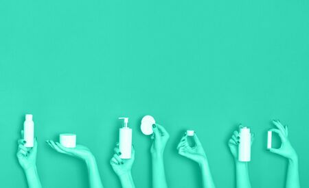Female hands holding cosmetics bottles - lotion, cream, serum on mint color background. Trendy green and turquoise color. Skin care, pure beauty, body treatment concept. Banner with copy space.の写真素材