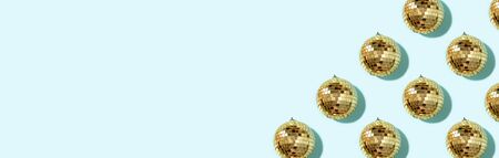 Creative Christmas pattern. Shiny gold disco balls over blue background. Flat lay, top view. New year baubles, star sparkles. Party time. Cristmas greeting card.の写真素材