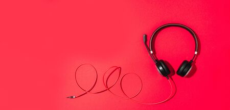 Music and sound concept. Style black headphones on red background. Top view. Copy space. Urban...