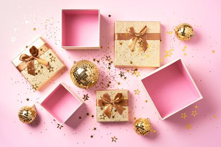 Gift box, shiny gold disco balls, sparkling gold glitter on pink background. New year baubles, star sparkles. New year, Christmas, Valentine's day concept of greetings. Copy text. Top view, flat layの写真素材