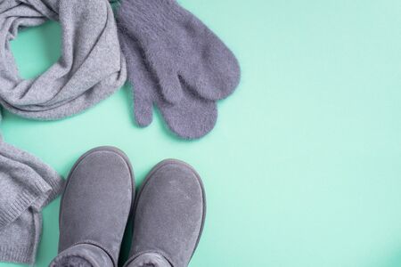 Fashion concept flat lay. Winter warm clothes flat lay on blue background. Wool feminine clothes sweater, scarf, boots. Top view, copy space. Banner.の写真素材