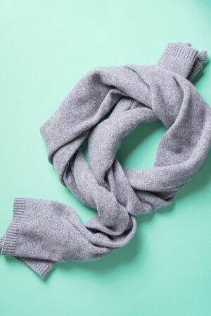 Grey knitted scarf on blue background. Top view, copy space. Winter warm clothes flat lay. Wool feminine clothes. Winter sale concept.の写真素材