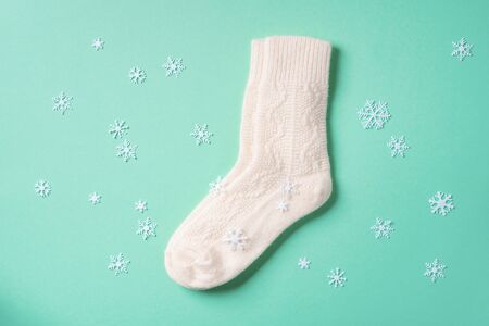 Pair of white woolen knitted socks on blue background. Top view. Copy space. Christmas and New Year cozy holiday composition. Winter weather.の写真素材