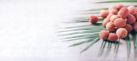 Lychee fruits with palm leaves on rattan background. Copy space. Exotic litchi, lichee fruits. Tropical food concept.の写真素材