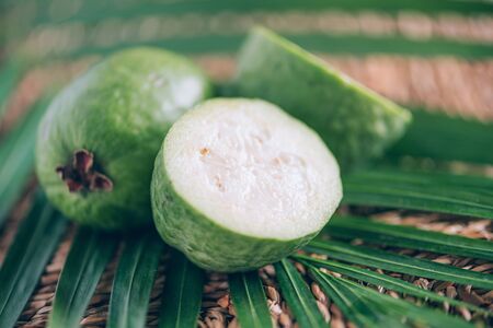 Tropical fruit feijoa over palm leaves on rattan background. Copy space. Acca sellowiana. Creative...