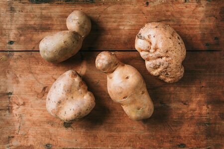 Ugly potatoes on wooden background. Ugly, unnormal vegetable, zero waste and plastic free concept. Top view. Copy spaceの写真素材
