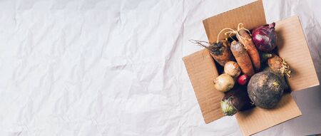 Donation box full of non gmo vegetables on craft paper background. Concept of zero waste production. Copy space. Compost and mold conceptの写真素材