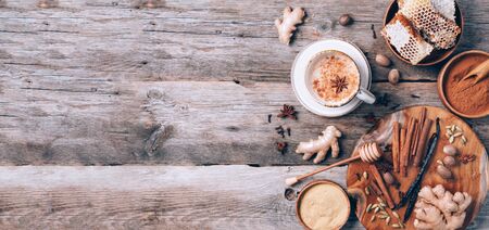 Tea with milk, cloves, ginger, cardamom, cinnamon, anise, vanile, honey, nutmeg. Indian masala tea with spices. Top view, copy space. Antiviral beverage. Healthy ayurvedic spice drink chaiの写真素材