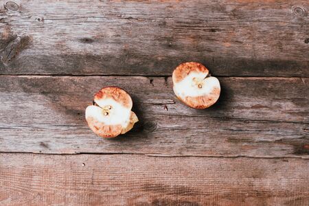 Spoiled bad red apple on wooden background. Garbage dump rotten food. Top view. Copy space. Rotten vegetables and fruits concept. Zero waste, compostの写真素材