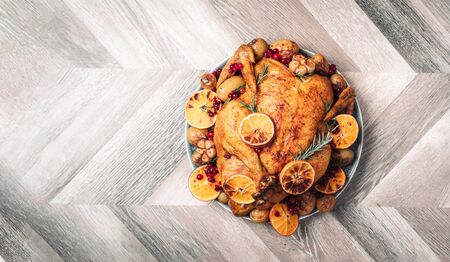 Whole roasted chicken with oranges, cranberries, spices and herbs. Copy space. Friends or family dinner. Festive Christmas table. Traditional Thanksgiving or Friendsgiving holiday celebration dishの写真素材