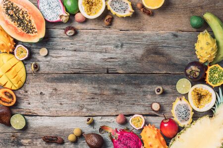 Exotic fruits - pineapple, papaya, mango, annona, banana, pitahaya, kiwano, african horned melon, tamarillo fruit, granadilla, salak, snake fruit, maracuya, rambutan, lychee, longan, tamarind, mangosteen on wooden background. Tropical fruits concept. Top view. Copy spaceの写真素材