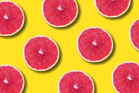 Grapefruit pattern on yellow background. Top view. Creative design, minimal flat lay concept. Summer time. Tropical travel, exotic fruit. Vegan and vegetarian foodの写真素材