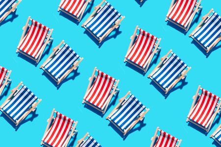 Deck chairs pattern on blue paper background. Flat lay and copy space. Summer travel vacation concept. Creative design, minimal flat lay concept. Minimal composition. Summer time.の写真素材
