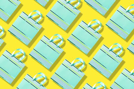 Top view of turquoise paper shopping bag pattern on trendy yellow background. Copy space. Creative...