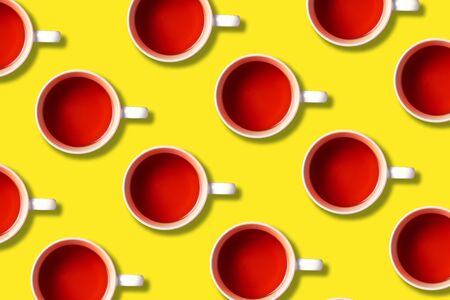 Pattern of tea cups on yellow background. Top view. Copy space. Creative design for packaging. Autumn or winter season concept.の写真素材