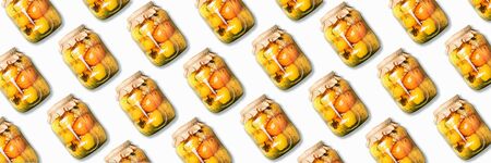 Pickled tomatoes in jar pattern on white background. Top view. Creative packing design. Canned and...