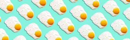 Fried egg or scrambled eggs pattern on blue background. Creative food concept. Top view. Conceptual trend. Banner. Keto diet. Healthy food print. Creative design for packagingの写真素材