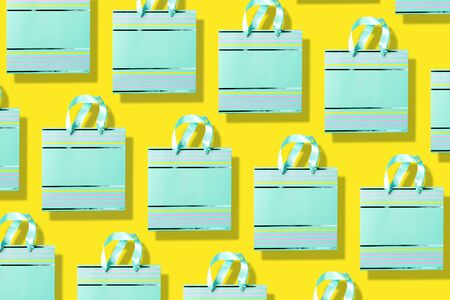Top view of turquoise paper shopping bag pattern on trendy yellow background. Copy space. Creative...