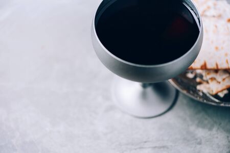 Communion still life. Unleavened bread, chalice of wine, silver kiddush wine cup on grey background. Christian communion concept for reminder of Jesus sacrifice. Easter passoverの写真素材