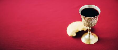 Unleavened bread, chalice of wine, silver kiddush wine cup on red background. Communion still life. Christian communion concept for reminder of Jesus sacrifice. Easter passover.の写真素材